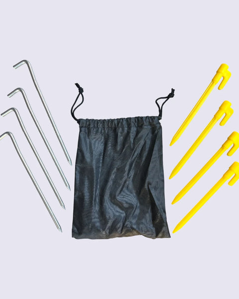 A black bag is placed beside four yellow plastic pegs and four steel pegs -for beachmats / picnic mats