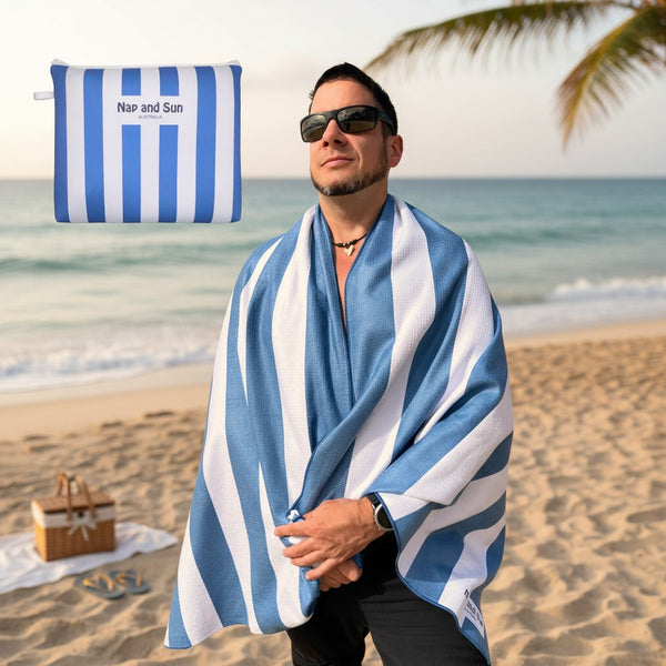 Man on a beach wearing a blue and white striped towel with a palm tree in the background.