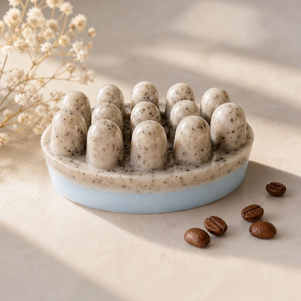 Handmade coffee soap bar with real coffee grounds, a natural speckled top and soft light blue base, styled on a beige surface with coffee beans and dried flowers.