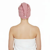 Person wearing a pink hair towel on their head with a white background