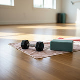 Floral gym towel with a dumbbell and yoga block on a wooden floor.