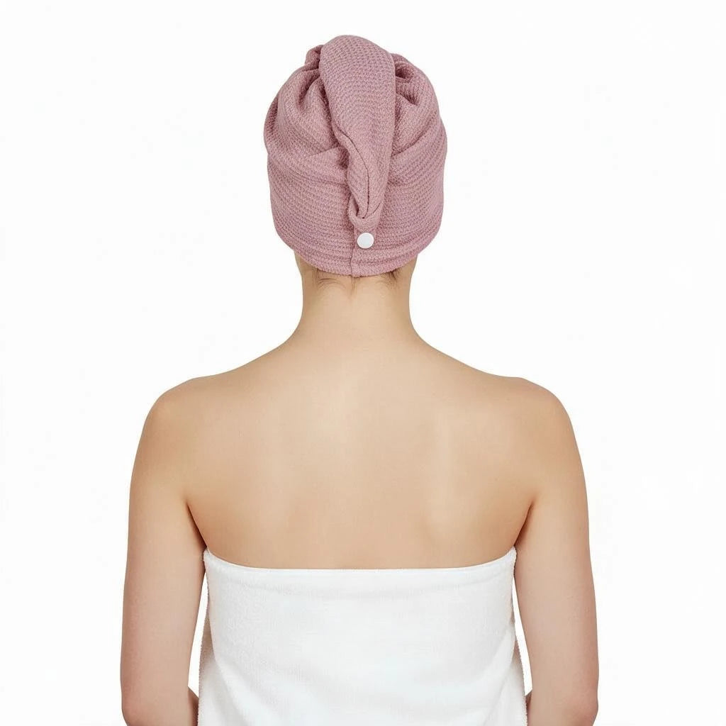 A person shown from the back wearing a dusty pink textured microfiber hair wrap on their head and a white towel around their shoulders, against a plain white background.