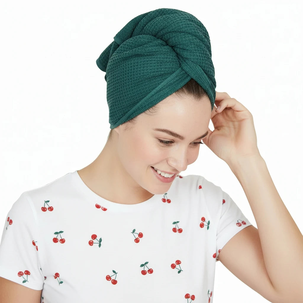 Woman wearing a teal hair towel on her head with a white shirt.