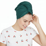 Woman wearing a teal hair towel on her head with a white shirt.