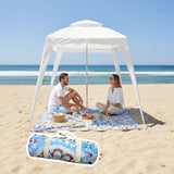 Two people sitting under a cabana on a mandala patterned picnic blanket at the beach.