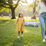 Woman and child walking in a park with a rolled-up picnic mat