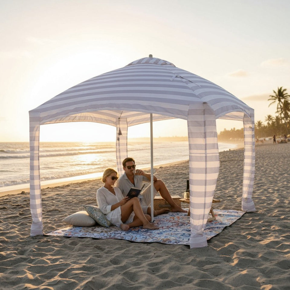  Two people sitting under a cabana on a mandala patterned picnic blanket at the beach