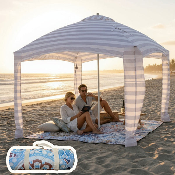Two people sitting under a cabana on a mandala patterned picnic blanket at the beach.