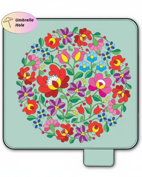 Colorful floral pattern picnic mat on a green background with an umbrella hole label.