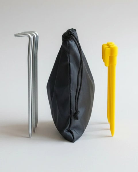 Black pouch with yellow sand pegs and metal pegs on a light gray background.