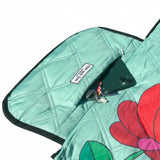 Close-up of a zip pocket on a picnic blanket with a phone and car key securely placed inside.