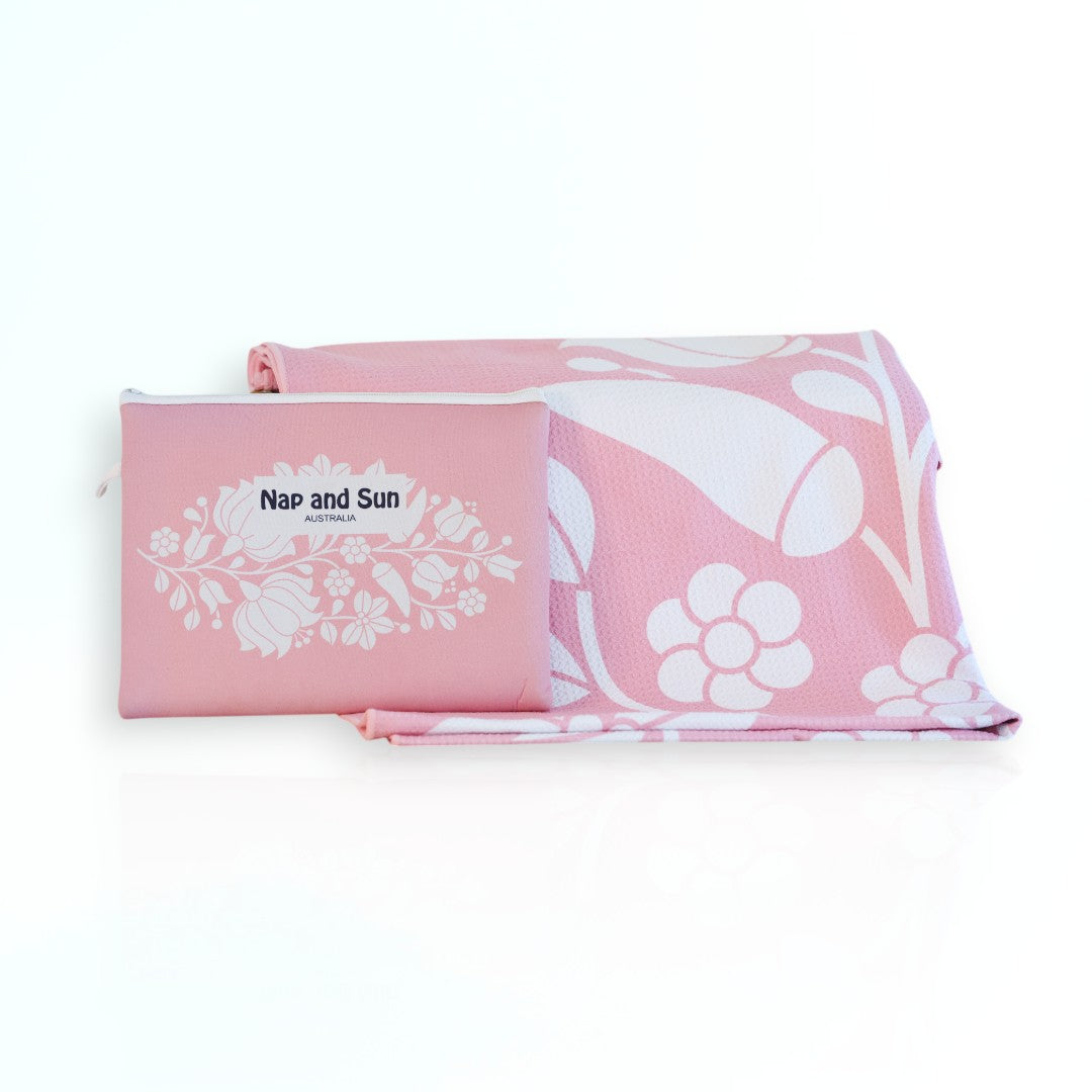 Nap and Sun Pink Bloom sand-free beach towel featuring a  soft pink background with white floral pattern. Free matching wetbag included. 