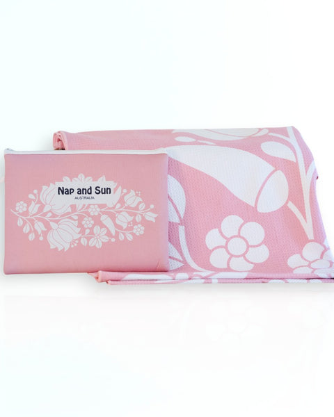 Nap and Sun Pink Bloom sand-free beach towel featuring a  soft pink background with white floral pattern. Free matching wetbag included. 