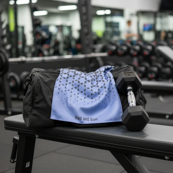 Blue patterned gym towel on a black gym bag with a dumbbell on a bench in the gym. 