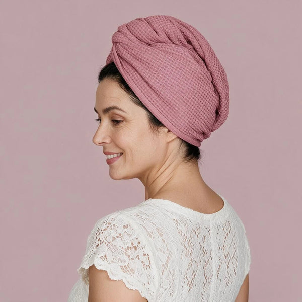 Woman wearing a dusty pink waffle wave hair wrap with a white lace top against a pink background.