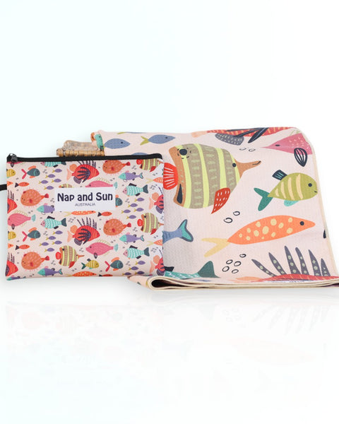 Nap and Sun Rainbow Reef sand-free beach towel for kids with a colorful underwater theme on the front, featuring vibrant coral, fish, and sea creatures on a light peachy background. Free matching wetbag included. 