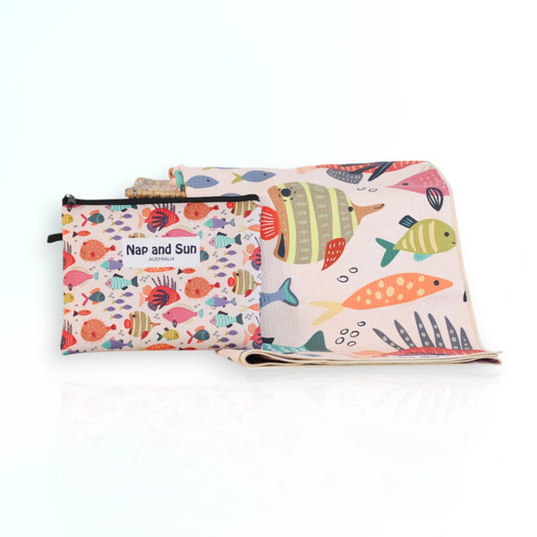 Nap and Sun Rainbow Reef sand-free beach towel for kids with a colorful underwater theme on the front, featuring vibrant coral, fish, and sea creatures on a light peachy background. Free matching wetbag included. 
