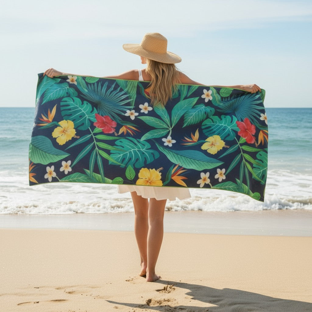 Woman stretching out a tropical-pattern towel on the beach under bright sunlight.