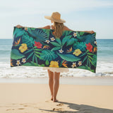 Woman stretching out a tropical-pattern towel on the beach under bright sunlight.