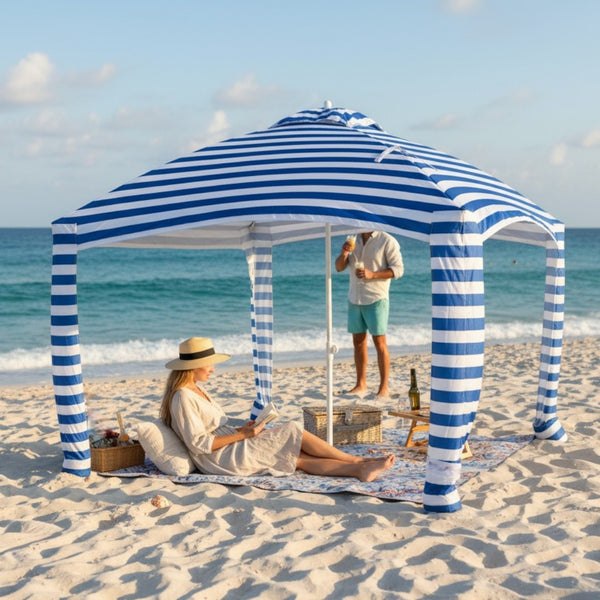 Mandala picnic blanket set up on a sandy beach under a cabana, with people relaxing and enjoying a picnic.