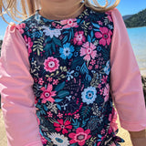 Person wearing a floral dress with pink sleeves and a blurred outdoor background