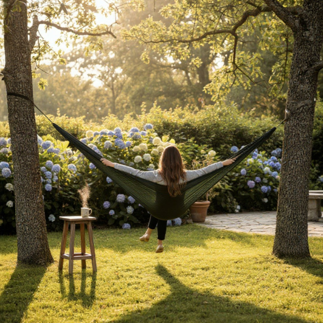 Woman relaxing in a hammock in a garden with flowers and trees