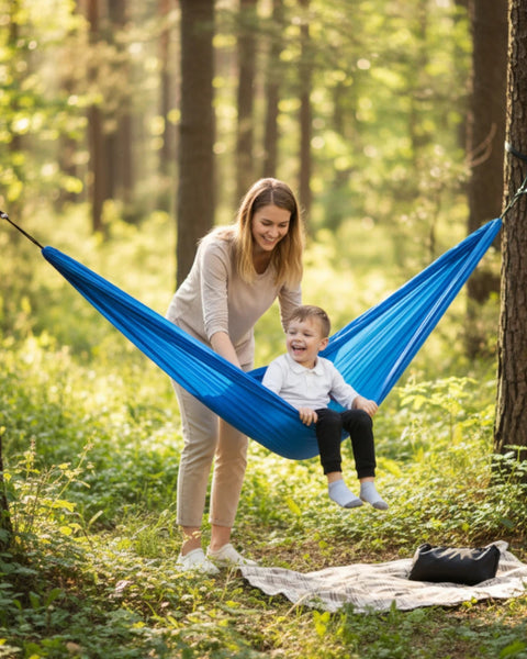 Woman and child in a blue hammock in a forest setting
