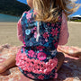 Child wearing a floral swimsuit with ruffles on a beach